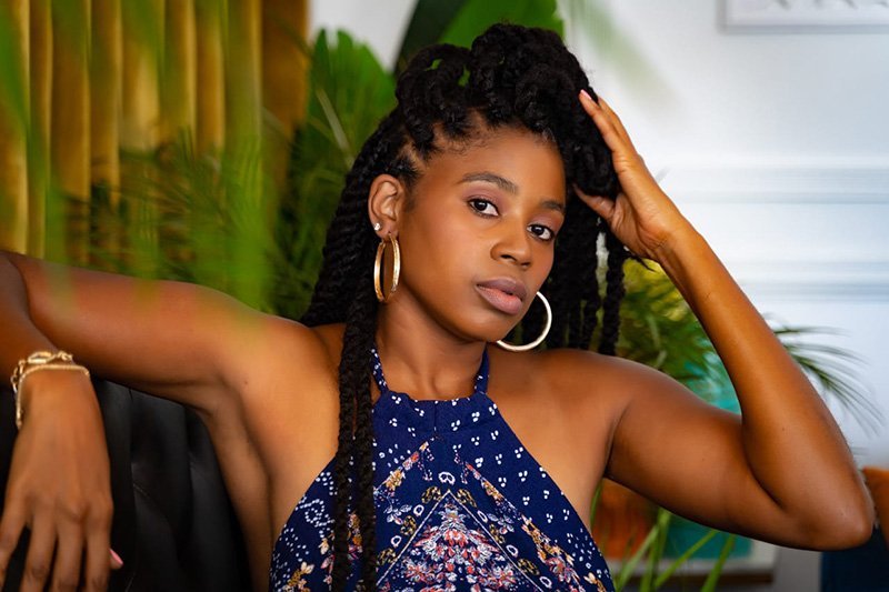 Lovett Love in a blue halter dress with gold hoop earrings