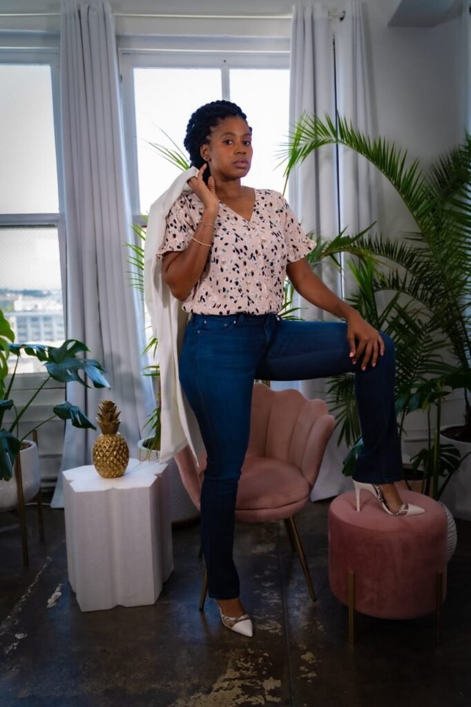 Lovett Love posed in a bright loft with palms, a pink velvet chair and a gold pineapple