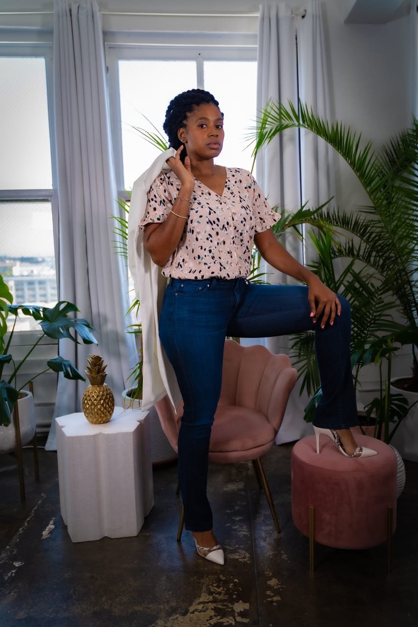 Lovett Love posed in a bright loft with palms, a pink velvet chair and a gold pineapple