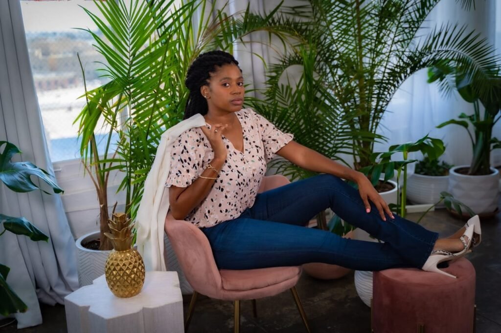 Lovett Love lounging in a pink velvet chair surrounded by palms