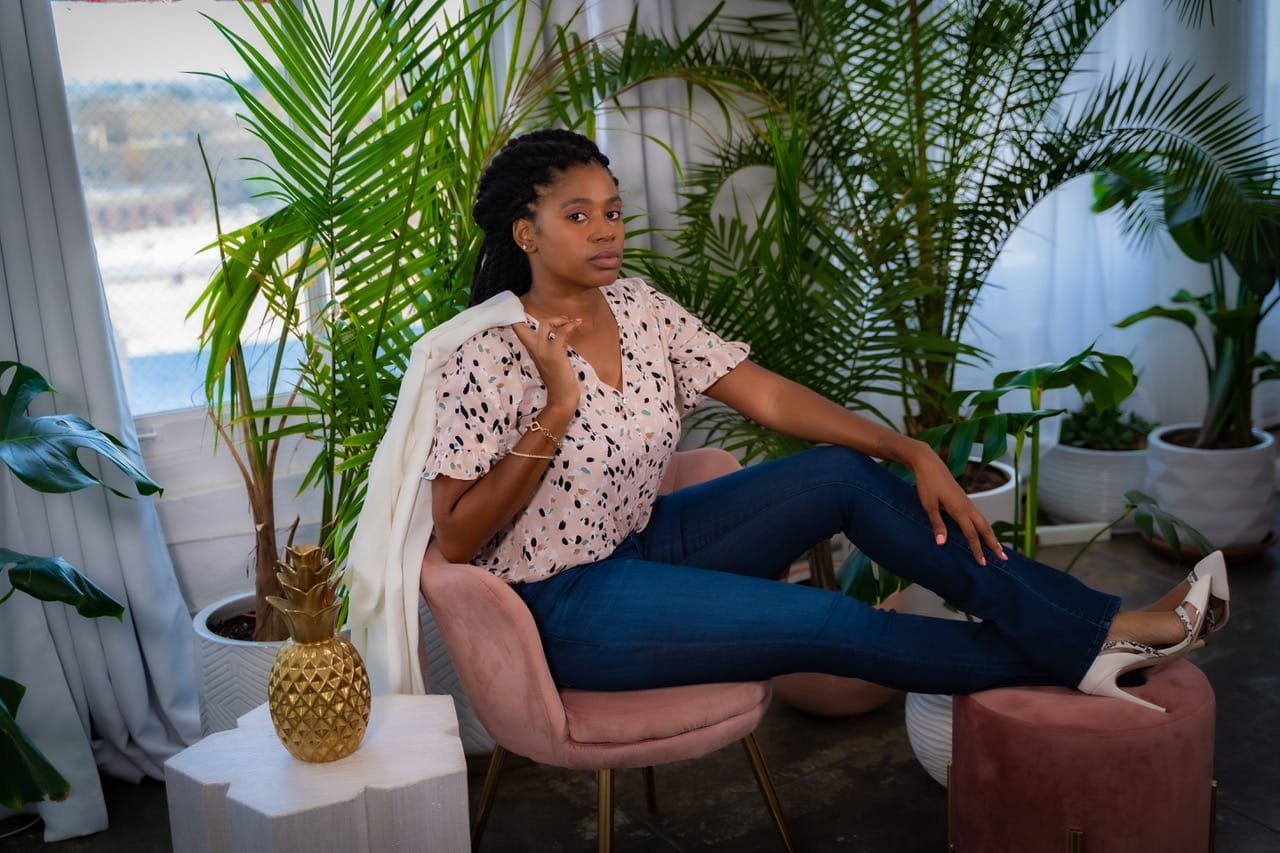 Lovett Love lounging in a pink velvet chair surrounded by palms